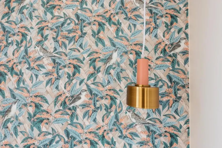 Dining room with teal and peach patterned wallpapering with birds and leaves